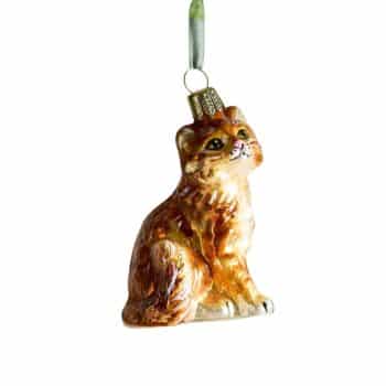 Brown cat glass Christmas ornament hanging from evergreen branches.