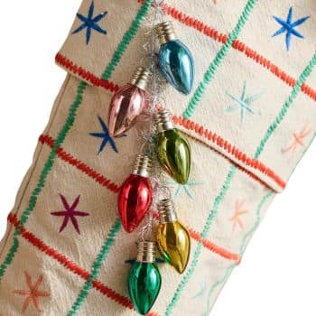 Colorful glass Christmas light bulb ornaments hanging from a stocking.