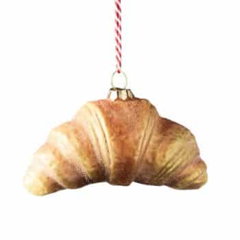 Croissant glass Christmas ornament hanging from a red and white striped cord.