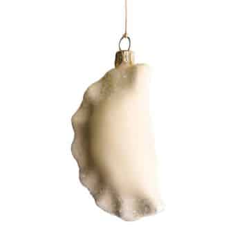 White dumpling glass ornament hanging from an evergreen branch.