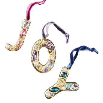 Gold jeweled letter ornaments spelling JOY with colorful velvet ribbons.