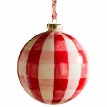 Red and white checkered glass Christmas ball ornament hanging on a tree.