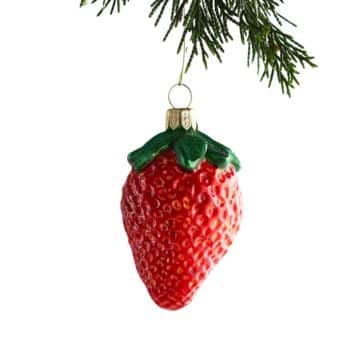 Red strawberry glass ornament hanging from an evergreen branch.