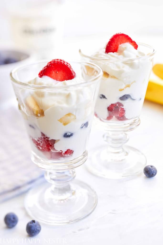 Two glass coupes filled with yogurt, berries, and fruit make for elegant holiday brunch ideas, topped with sliced strawberries.