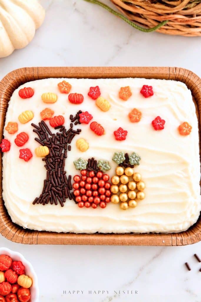 Trader Joe's pumpkin spice mini sheet cake decorated with a chocolate sprinkle tree, orange and red candy leaves, and copper and gold sugar pearl pumpkins.