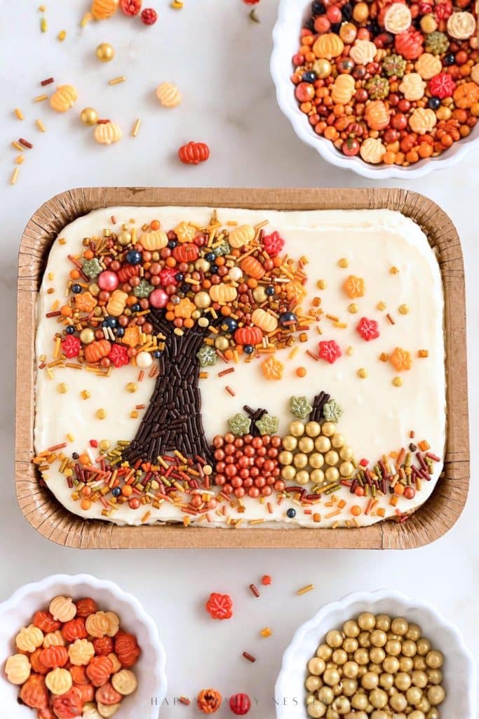 Trader Joe's sheet cake decorated with an autumn tree made from chocolate sprinkles, colorful candy leaves, and metallic pearl pumpkins.
